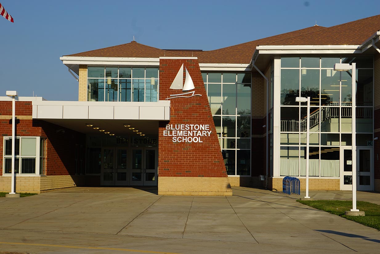 A brick elementary school stands under a clear, blue sky.